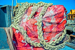 Colorful tarpaulin material and old thick rope